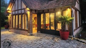 Un bâtiment traditionnel à colombages, doté d’un patio couvert, de grandes fenêtres et de plantes en pot.