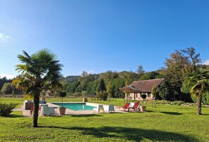 A pool area with lounge chairs and a house in the background.