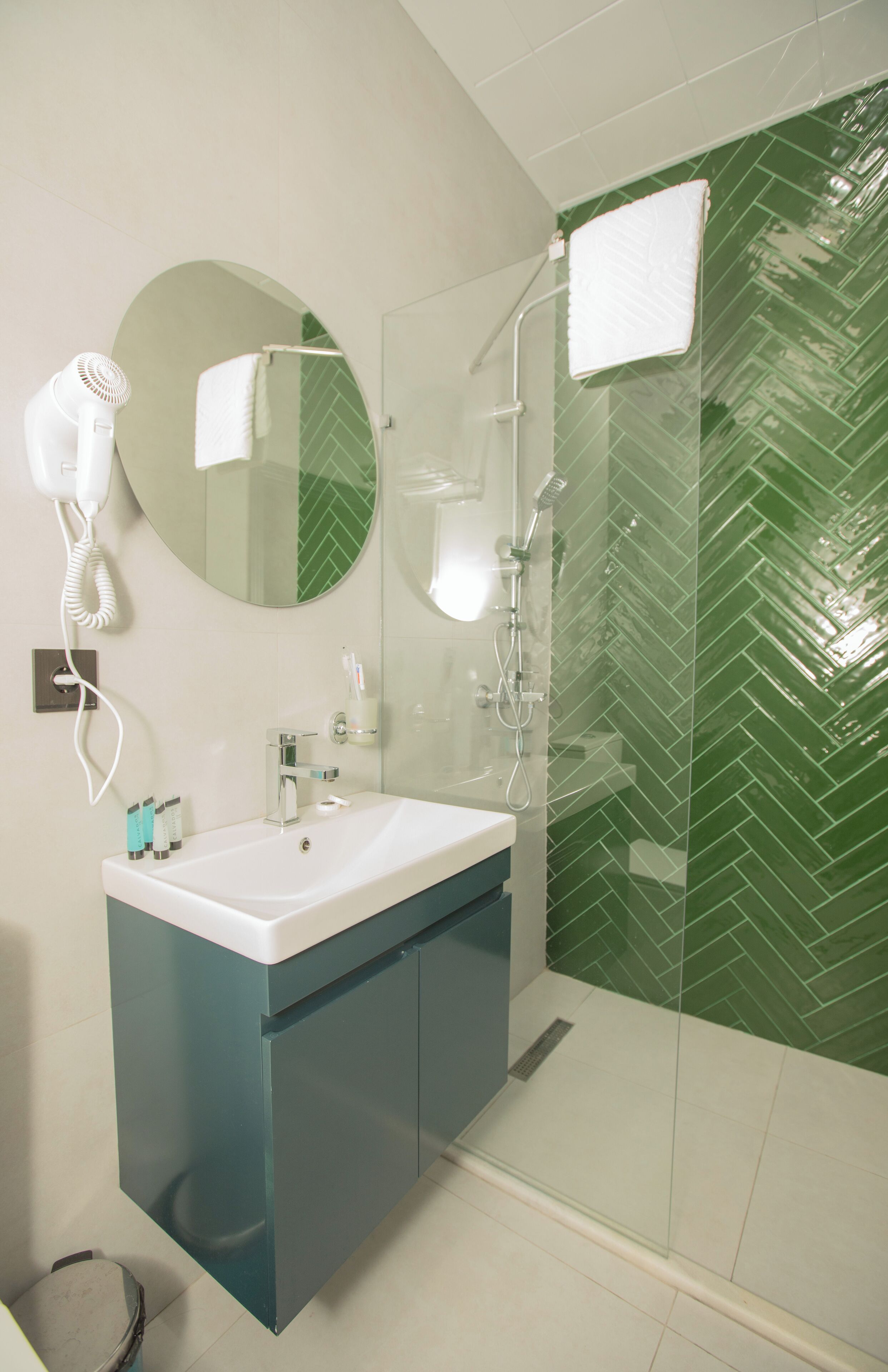 Un baño con lavabo, espejo, secador de pelo y ducha.