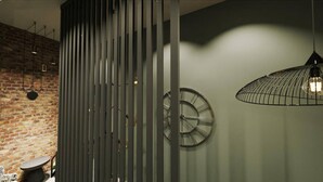 A modern interior with a brick wall, a vertical panel, a round clock, and a hanging light fixture. - Twelve Inn Hotel (Baku)