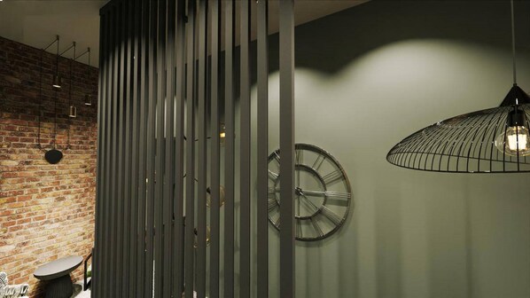 A modern interior with a brick wall, a vertical panel, a round clock, and a hanging light fixture. - Twelve Inn Hotel (Baku)