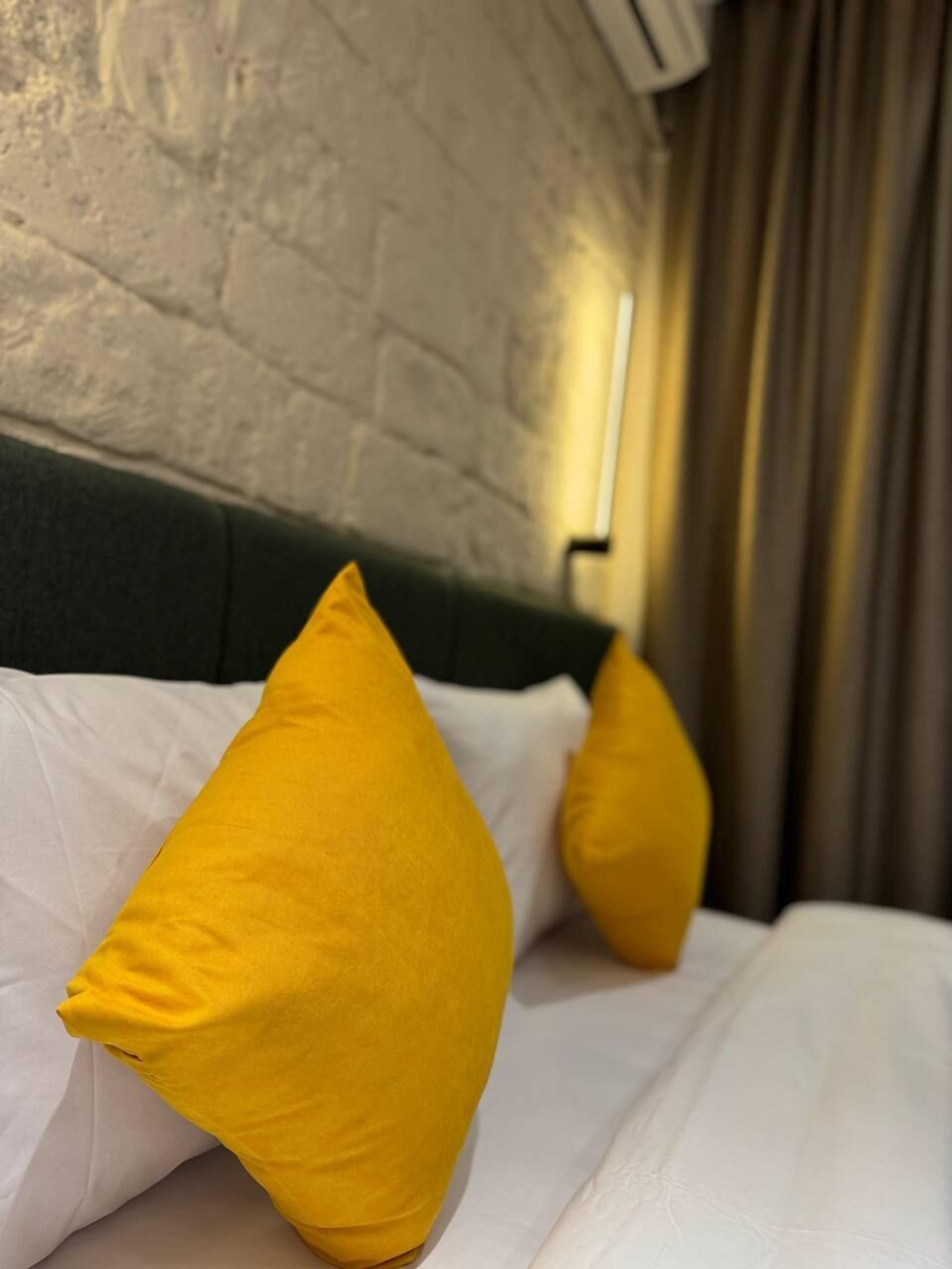 Una cama con ropa de cama blanca y dos almohadas amarillas.