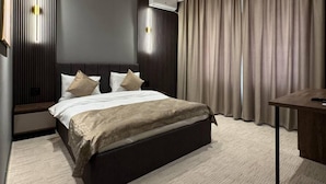 A modern bedroom with a large bed, dark headboard, and a desk with a chair. - Twelve Inn Hotel (Baku)