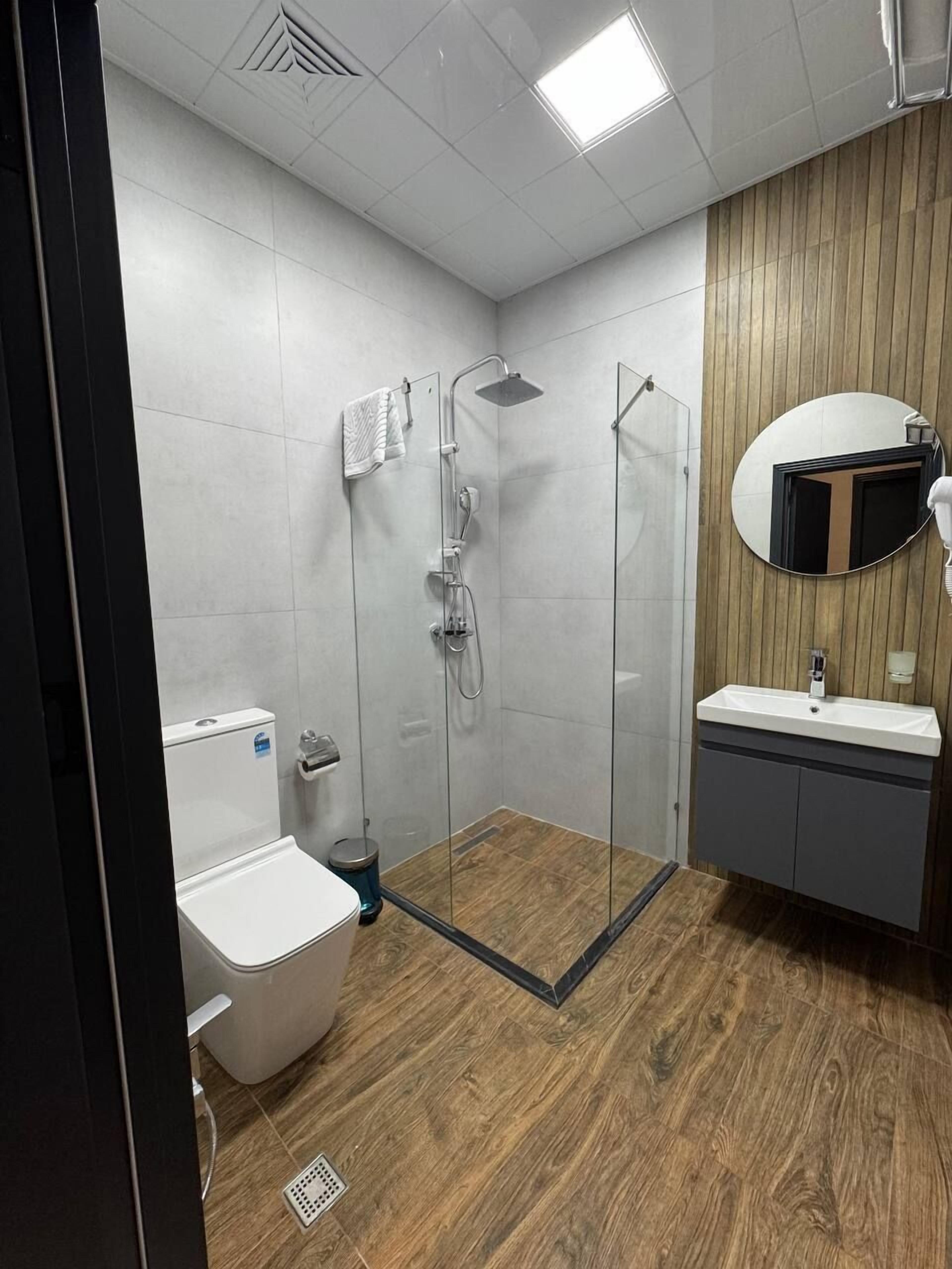 Une salle de bain moderne avec une douche à parois de verre, des toilettes blanches et un meuble-lavabo avec un miroir.