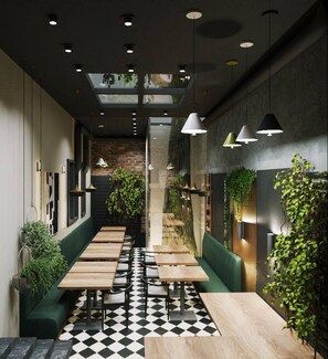 A restaurant with a checkered floor, wooden tables, green booths, pendant lighting, and plants. - Twelve Inn Hotel (Baku)