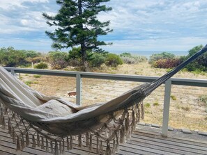 Eine Hängematte auf einer Holzterrasse mit Blick auf das Meer und die umliegende Vegetation.