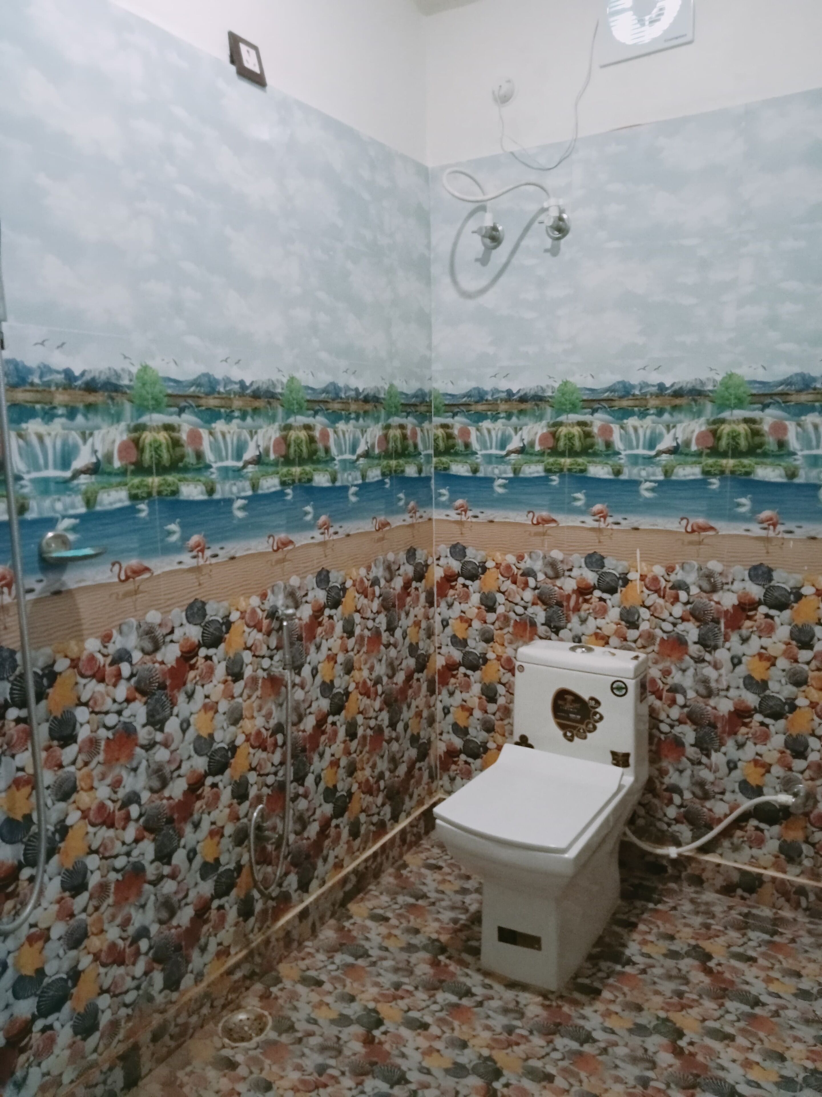 A bathroom with a toilet, shower, and a wall with a nature-themed mural.