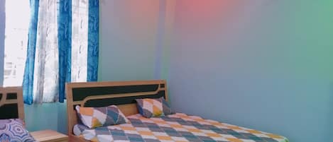A bedroom with two beds, a ceiling fan, and a window with curtains.