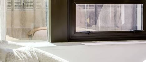 Una habitación con un ventanal grande, una silla blanca y un sofá blanco.