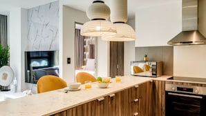 A modern kitchen with a marble countertop, wooden cabinets, a built-in oven, and pendant lighting. - Contemporary Comfort at City Suite 905 (Cape Town)