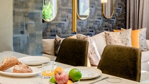 Et moderne hotelværelse med en marmor-morgenmadsbar, et stort spejl og et hyggeligt siddeområde med sofa og stole.