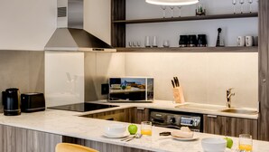 A modern kitchen with a central island, built-in appliances, and a breakfast setup. - Upscale Urban Haven at City Suite 906 (Cape Town)