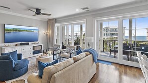 Un salon spacieux doté d’un grand téléviseur à écran plat, de sièges confortables et d’un balcon offrant une vue sur l’océan.