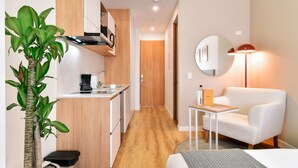 A compact hotel room with a kitchenette, a white sofa, a round mirror, and a small table. - w Amazing Loft w Balcony in Chapinero (Bogotá)
