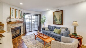 A living room with a fireplace, a sofa, a coffee table, and a lamp. - Quiet Condo w/ Pool Access, Near Arizona Boardwalk (Scottsdale)