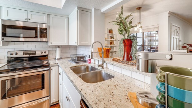 A modern kitchen with stainless steel appliances, white cabinetry, and a granite countertop. - Quiet Condo w/ Pool Access, Near Arizona Boardwalk (Scottsdale)
