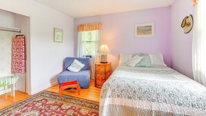 A bedroom with a bed, a chair, a nightstand, a lamp, and a window with curtains. - 1440 Getaway w/ Yard & Deck ~ 16 Mi to Rochester (Rush)