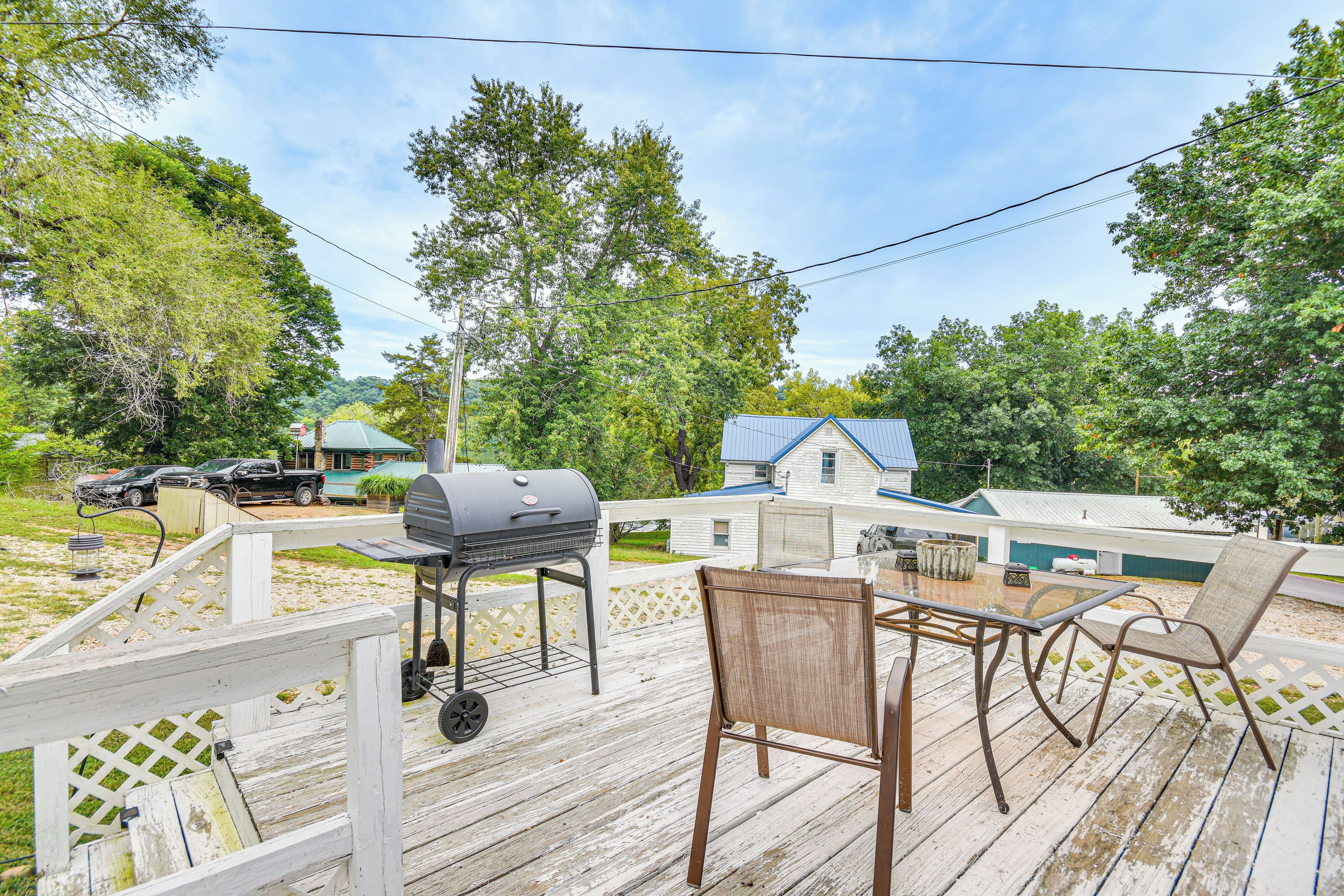 A wooden deck with a grill, chairs, and a table.