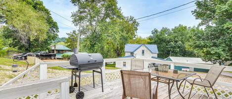 A wooden deck with a grill, chairs, and a table.