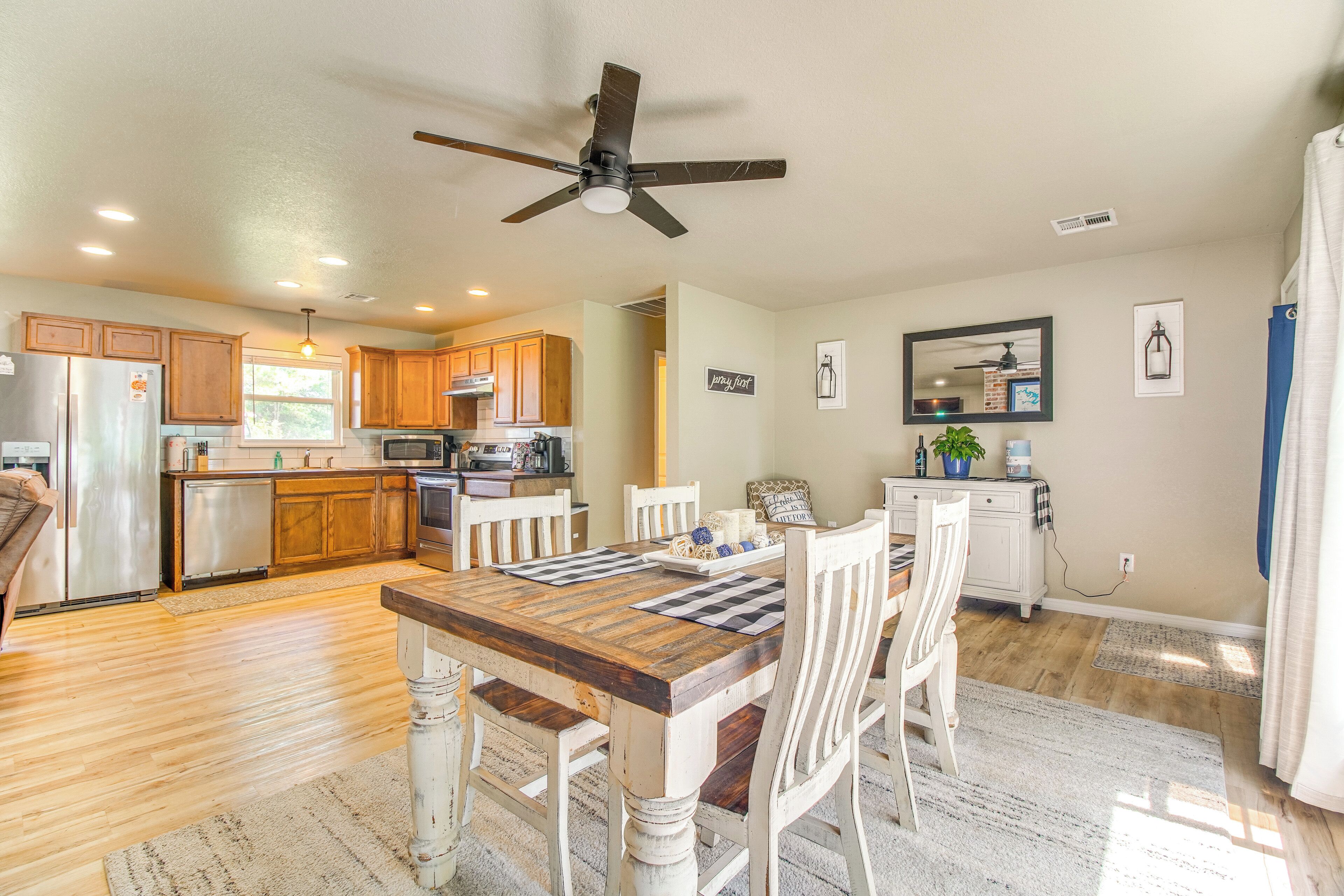 A spacious kitchen with wooden cabinets, a dining table with chairs, a ceiling fan, and a refrigerator.