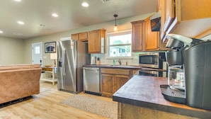 A modern kitchen with wooden cabinets, stainless steel appliances, and a large island with a coffee maker. - On-site Lake Access: Pet-friendly Vinita Home (Ketchum)