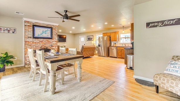 A spacious kitchen with modern appliances, a dining area with a wooden table and chairs, and a cozy living area with a sofa and a motivational sign. - On-site Lake Access: Pet-friendly Vinita Home (Ketchum)