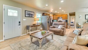 A spacious living room with a wooden coffee table, a brown leather sofa, and a kitchen in the background. - On-site Lake Access: Pet-friendly Vinita Home (Ketchum)