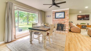 A spacious living room with a fireplace, a dining area with a table and chairs, and a large window with curtains. - On-site Lake Access: Pet-friendly Vinita Home (Ketchum)