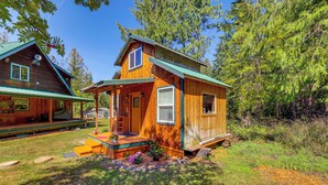 Eine Holzhütte mit Veranda, überdachter Terrasse und einem kleinen Garten mit Blumen.