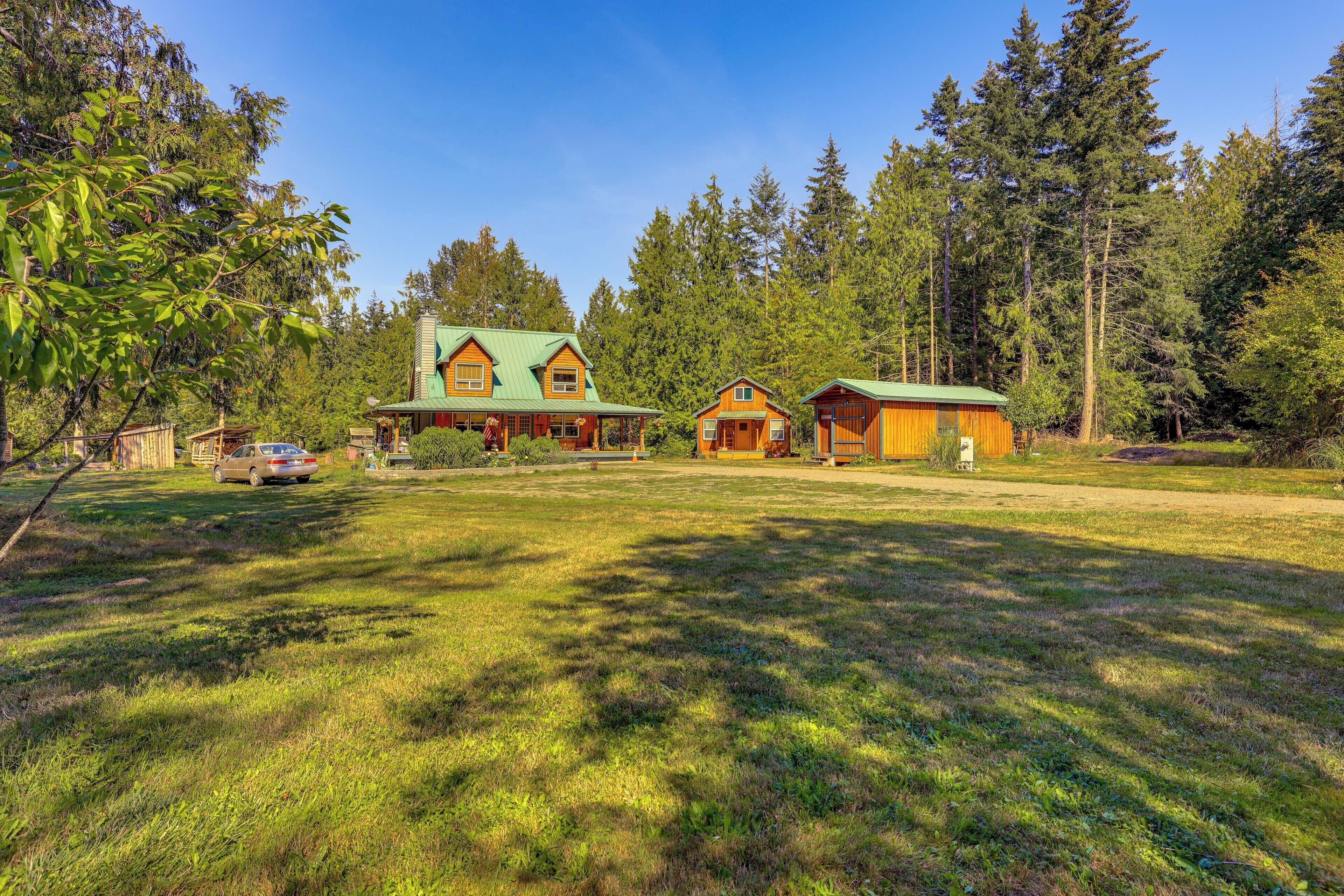 A large house with a green roof, surrounded by a grassy yard and tall trees.