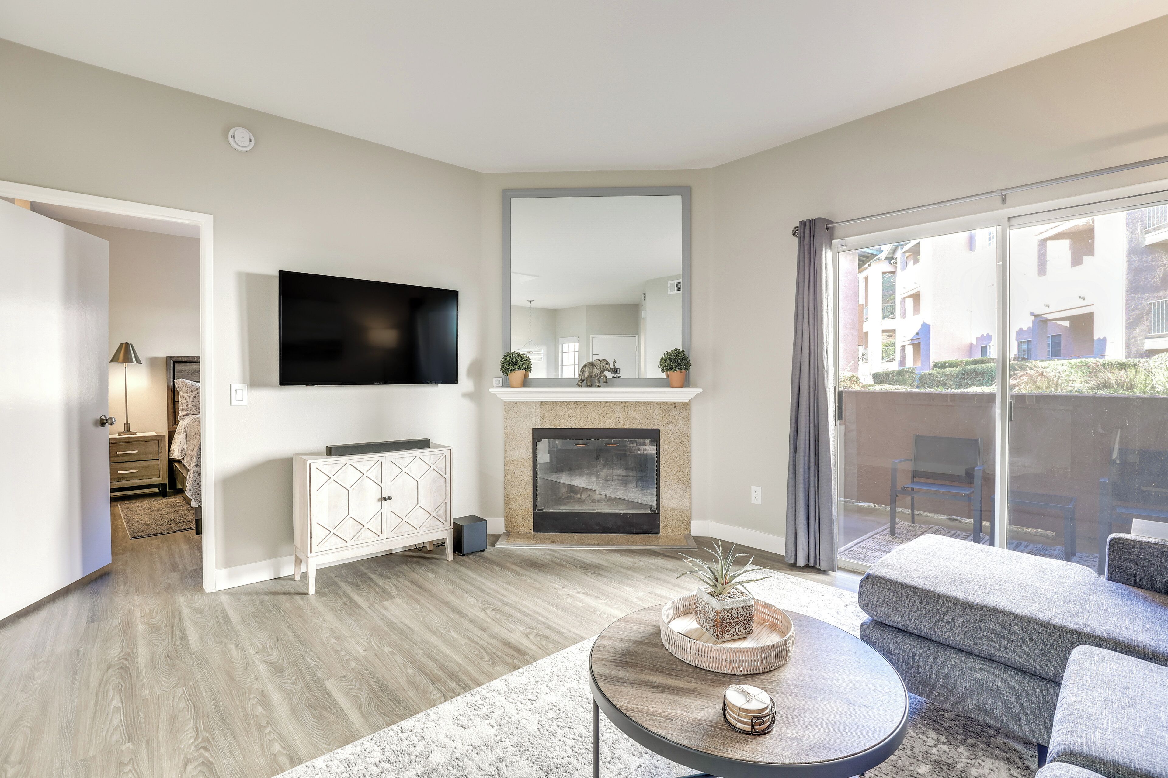 A modern living room with a fireplace, a flat-screen TV, and a balcony with outdoor furniture.
