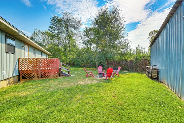 A backyard with a lawn, a wooden deck, and a metal building. - Rural Escape Near Lake Ouachita w/ Gas Grill! (Royal)