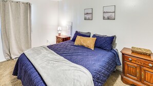 Ein Schlafzimmer mit einem Bett, einem Nachttisch, einer Kommode und zwei Bildern an der Wand.
