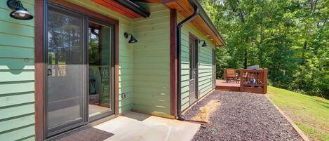 A house with a green exterior, a covered porch with chairs, and a wooden deck.