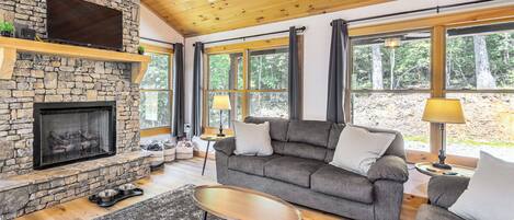 A cozy living room with a stone fireplace, a grey sofa, and a wooden coffee table.