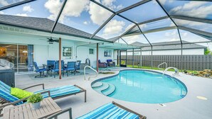 A covered outdoor swimming pool with lounge chairs and a barbecue area.