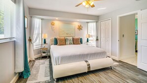A bedroom with a bed, bedside tables, a ceiling fan, and a window with curtains.
