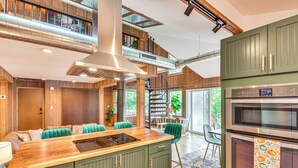 Een moderne keuken met een centraal eiland, groene kastjes en roestvrijstalen apparatuur.