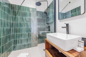 A modern bathroom with a large white sink, a wooden vanity, a mirror, and green-tiled walls. - Résidence Neuilly BLOUD (Neuilly-sur-Seine)