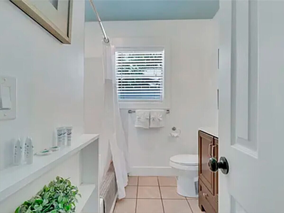 Ein kleines Badezimmer mit Toilette, Duschvorhang, Fenster und Waschbecken.