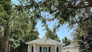 A residential property with a wooden fence, a paved driveway, and a house with a gabled roof. - Luna Bungalow | New Orleans Soul Meets Gulf Coast Charm in Historic Pensacola (Pensacola)