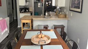 A dining area with a wooden table, two placemats, and a fruit tray. - Luna Bungalow | New Orleans Soul Meets Gulf Coast Charm in Historic Pensacola (Pensacola)