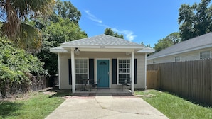 A single-story house with a front porch, a blue door, and a number '1719A' on the roof. - Luna Bungalow | New Orleans Soul Meets Gulf Coast Charm in Historic Pensacola (Pensacola)