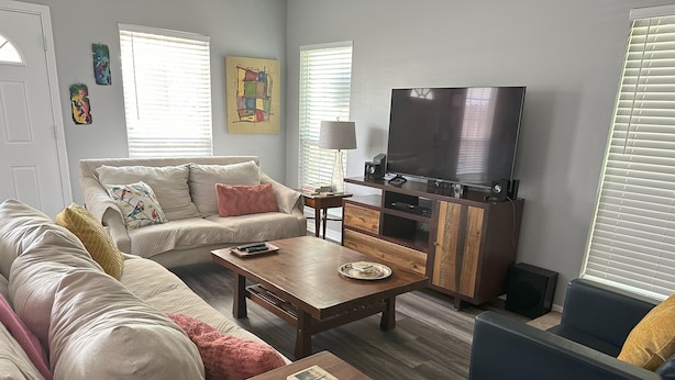 A living room with a sofa, coffee table, and TV. - Luna Bungalow | New Orleans Soul Meets Gulf Coast Charm in Historic Pensacola (Pensacola)