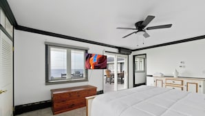 A bedroom with a bed, a wooden dresser, a ceiling fan, and a window with blinds.