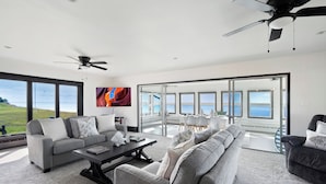 A spacious living room with a large window overlooking a scenic view, a ceiling fan, and a modern interior design.