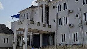 A multi-story residential building with a balcony, air conditioning units, and a covered entrance. - Camas Hotel and Suites (Abeokuta)