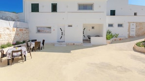 A two-story building with a patio area featuring outdoor seating and a stone wall.