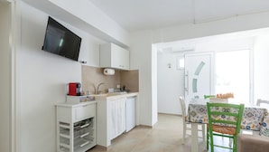 A compact kitchen with a TV, white cabinets, a sink, and a dining area with a table and chairs.