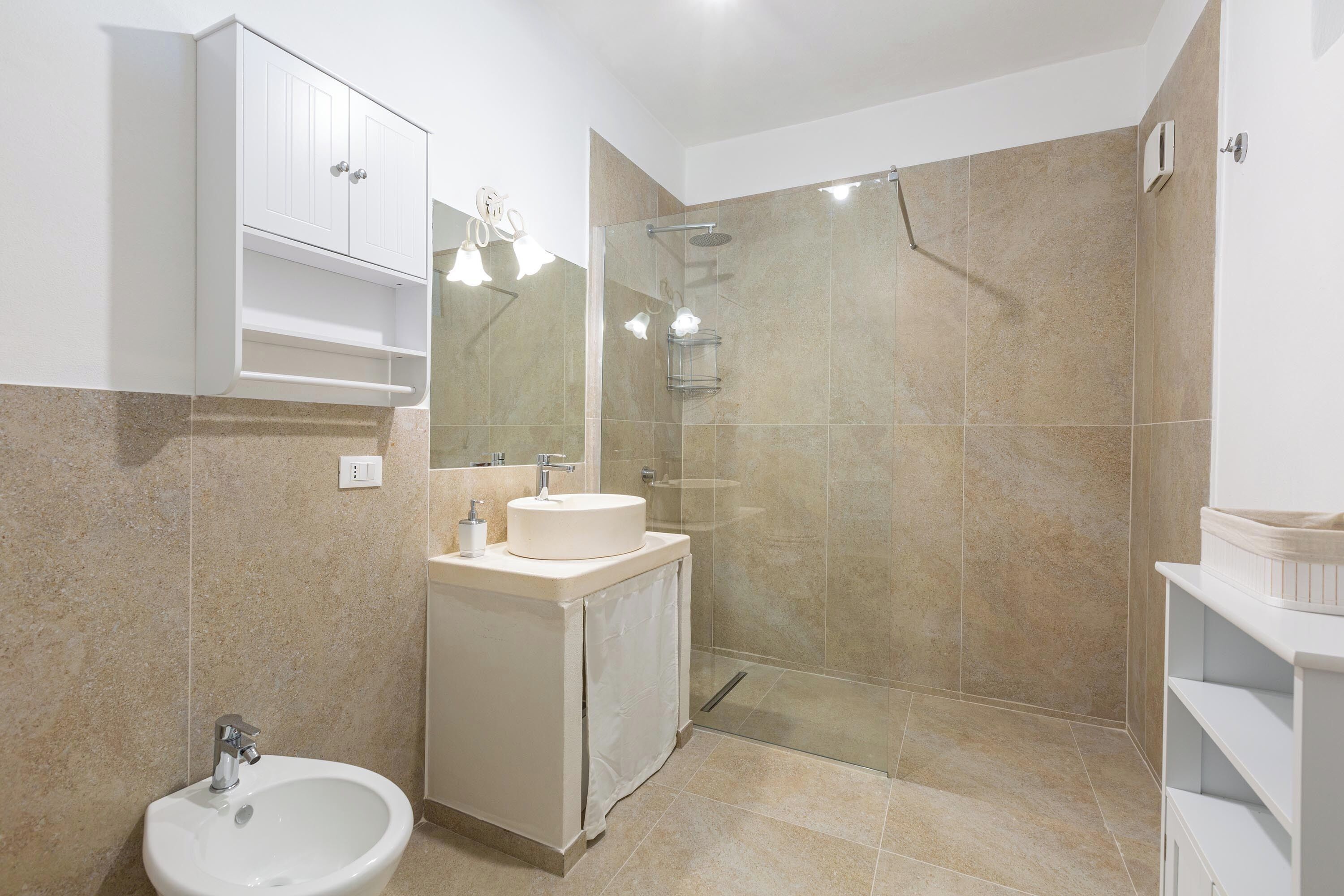 Een moderne badkamer met een wastafel, spiegel en douche.